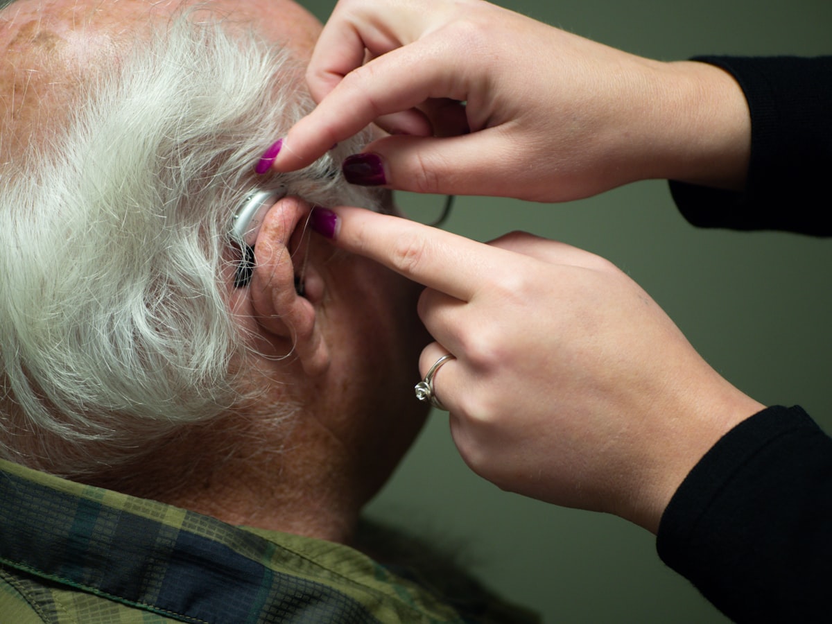 hearing aid being fitted on an elderly man's ear